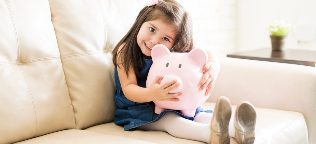 Lovely little girl with her piggy bank at home