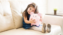 Lovely little girl with her piggy bank at home